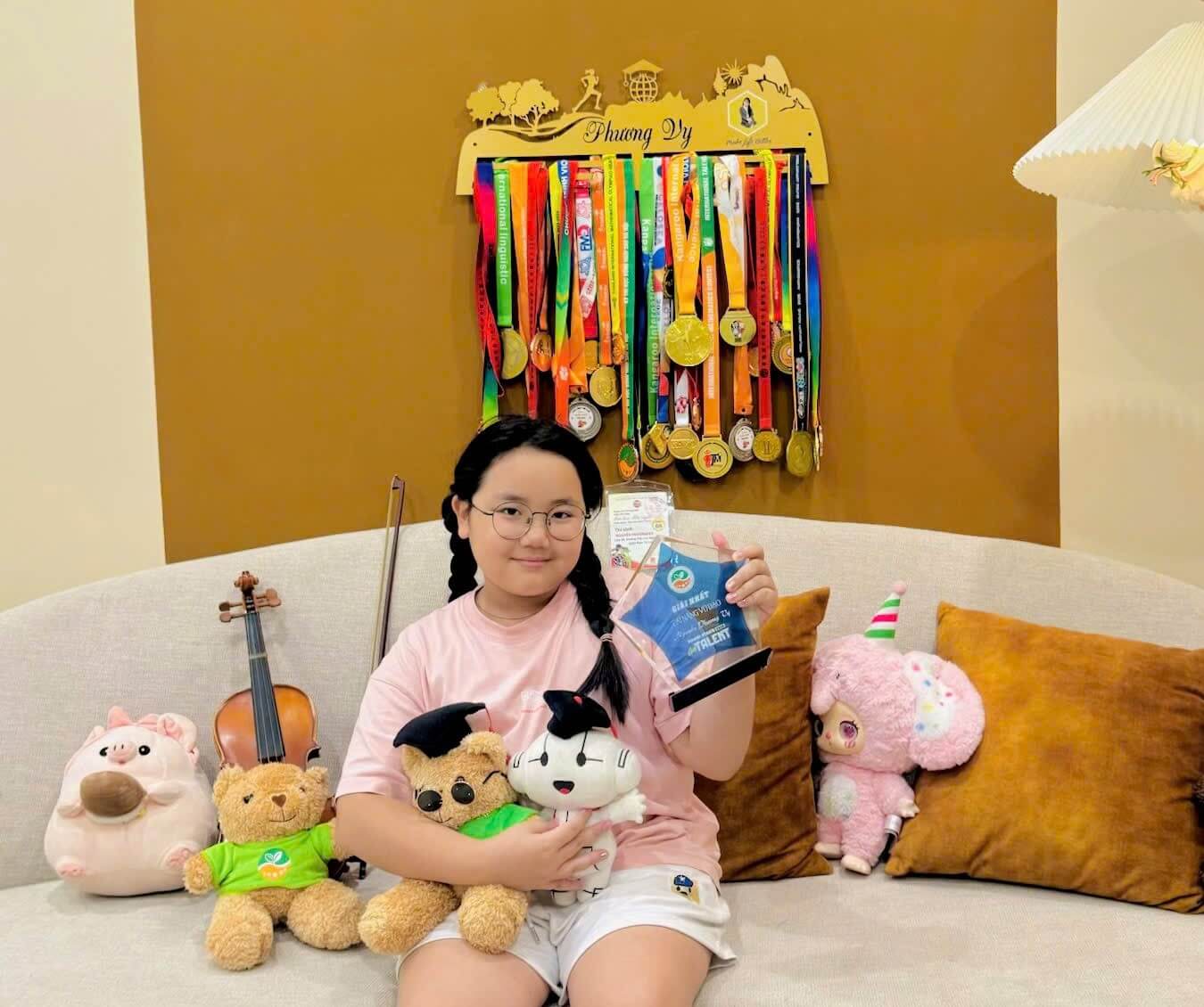 Phương Vy chụp ảnh lưu niệm cùng bộ sưu tập huy chương, cúp đã giành được qua các kỳ thi